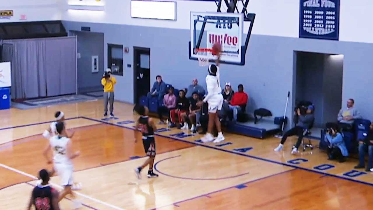 player about to dunk a basketball while other players run toward the basket.